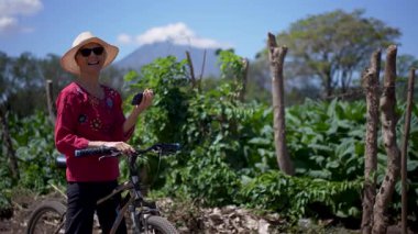 Gülümseyen kadın portresi bisikletiyle Nikaragua 'daki Ometepe Adası' nın canlı manzarasını gözler önüne seriyor. Concepcion Volkanı Orta Amerika 'da görkemli bir şekilde yükseliyor..