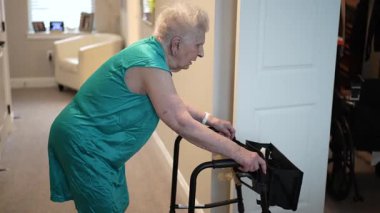 90 'lı yaşlarda yaşlı bir kadın aile evine taşınmak için yürüteç kullanıyor. Öğleden sonra kararlılığını ve bağımsızlığını gösteriyor..