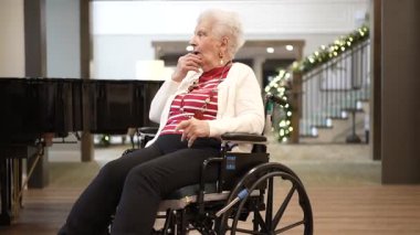 Columbia, MD, ABD - 12252024: Yaşlı bir kadın bakım evinde bir aile üyesi tarafından çalınan piyano müziğinden hoşlanıyor. Sıcak atmosfer bir aile ziyareti sırasında birlikteliği teşvik eder..