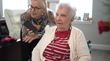 90 'lı yaşlarda yaşlı bir kadın, aile sevgisinin ve yakınlığının sıcaklığını yakalamak için, oturma odasında telefonla ailesini arayan kızıyla neşeli bir anı paylaşıyor..