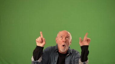 Olgun bir adam ellerini havaya kaldırarak coşku gösteriyor. Yüzünde şaşırmış bir ifade var..