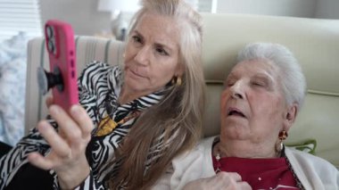 90 'lı yaşlarda yaşlı bir kadın bir koltukta oturmuş, nişanlı ve duygusal olarak bağlı görünen kızıyla samimi bir görüntülü konuşma yapıyor..