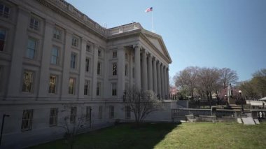 Washington, DC, ABD - 03 21 2025: ABD Hazine Bakanlığı Washington DC 'deki neoklasik mimarisini, tomurcuklanan ağaçlar ve ilkbaharın başlarında açık gökyüzü ile gösteriyor.