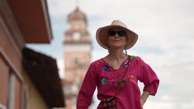 Parlak giyinmiş olgun kadın portresi, Nikaragua Granada 'daki Xalteva Kilisesi' nin önünde sevinçle duruyor ve seyahat deneyiminin özünü yansıtıyor..