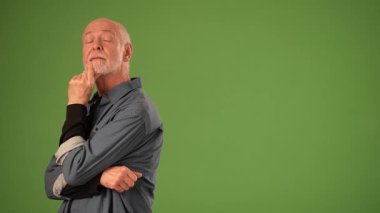 Kıdemli adam kollarını kavuşturup derin duygular ve düşünceleri yansıtıyor. Katı yeşil ekran arkaplanı duyurularda veya ürünlerde çok yönlü kullanımına izin verir.