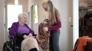 Bakıcı, yaşlı bir kadına evinde renkli bir kıyafet seçmesinde yardımcı olur. Sıcak atmosfer giyinirken anlamlı etkileşimlerini arttırır..