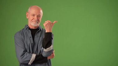 Olgun bir adam, elleri ile anlamlı bir jest sunar. Saf yeşil bir ekranın önünde güvenle durur ve duyurular için mükemmel bir ortam yaratır..