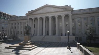 Washington, DC, ABD - 03 21 2025: Hazine Bakanlığı Washington DC 'de bahar güneşiyle aydınlanan bir binadır. Öndeki bir heykel, federallere tarihsel bağlam katıyor.