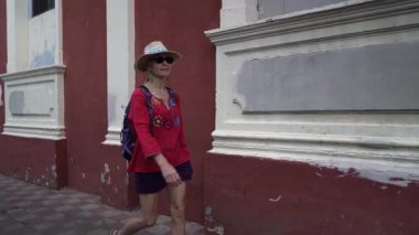 Olgun bir kadın, Granada, Nikaragua 'da renkli bir duvarda yürüyor ve bu tarihi Orta Amerika şehrinde kültürel deneyimlerinin tadını çıkarıyor..