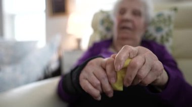 Yaşlı bir insan rahatça oturur ve iki eliyle oyun hamuru yoğurur. Faaliyet rehabilitasyon süresince el gücünü ve el becerisini artırmaya odaklanıyor..