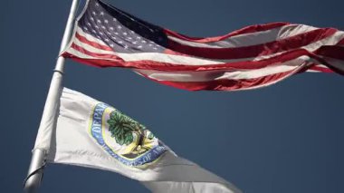 ABD ve ABD Eğitim Bakanlığı bayraklarının yavaş hareket eden görüntüsü Washington DC 'deki hükümet binasının önündeki açık mavi gökyüzüne gururla el sallıyor..