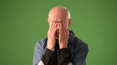 Olgun, yaşlı bir adam bir not defterine not alırken derin düşünceler içinde belirir. Saf yeşil ekran arka planı onun konsantrasyonunu ve duygularını vurguluyor..