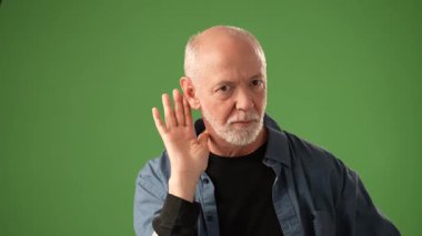 Olgun bir adam merakını düşünceli bir ifadeyle gösterir, elleri kulağına kadar kaldırılmış, üzücü sırları dinleyen, parlak yeşil bir perdeye dayanan, sağlam bir arka plan. Duruşu nişan taşıyor..