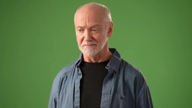 Gri saçlı olgun bir adam, soğuk algınlığıyla burun sümkürerek ve öksürerek yeşil bir zemine dayanıyor ve ifadesi için canlı bir atmosfer yaratıyor..