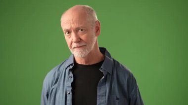 Olgun ve sakallı bir adamın POV 'u, katı yeşil perde arkaplanının önünde dururken anlamlı bir şekilde ifade eder. Duygularını ve bağlılığını gösterir..