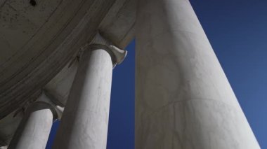Jefferson Memorial Düşük açılı beyaz mermer sütunlar açık mavi gökyüzüne uzanan, kayanın pürüzsüz dokusu ve sahnenin sadeliği görkemli ve zamansız bir mimariyi çağrıştırıyor..