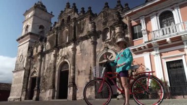 Mutlu bir turist telefonu ile Granada, Nikaragua 'daki La Merced Kilisesi' nin önünde selfie çeker. Bisiklete biniyor ve açık hava deneyiminin tadını çıkarıyor..