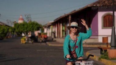 Olgun bir kadın bisikletini Granada, Nikaragua 'da Calzada' nın büyüleyici caddelerinde sürüyor. Güneşli bir günde Orta Amerika 'nın kültürünün ve güzelliğinin tadını çıkarıyor..