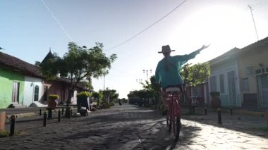 Olgun bir kadın, güneşli bir günde Orta Amerika 'nın cazibesini tecrübe ederek La Merced, Granada, Nikaragua' nın pitoresk Calzada caddelerinde bisiklet sürmekten hoşlanır..