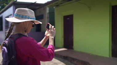 Güneş şapkalı neşeli, olgun bir kadın Ometepe, Nikaragua 'daki Moyogalpa' nın canlı renklerini yakalıyor ve güneşin altındaki yolculuğunun tadını çıkarıyor..
