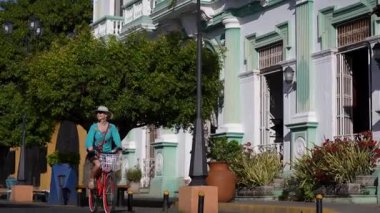 Bir kadın bisikletini Granada, Nikaragua 'nın canlı caddelerinde sürüyor, Orta Amerika' nın yerel kültürünü ve güzelliğini yaşıyor..