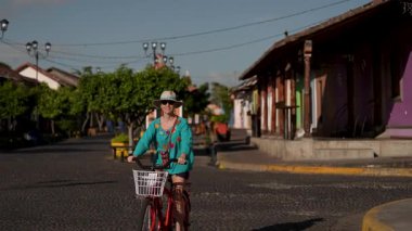 Olgun bir kadın, Nikaragua Granada 'nın canlı sokaklarında bisiklet macerasından zevk alır. Orta Amerika' ya yaptığı seyahatler sırasında yerel kültürü tecrübe eder..