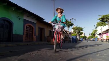 Olgun bir kadın bisikletiyle Granada, Nikaragua 'nın canlı Calzada sokaklarında geziyor ve tarihi La Merced kilisesinin yakınlarındaki açık hava deneyiminin tadını çıkarıyor..
