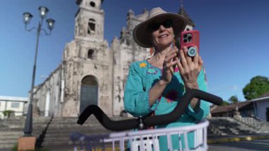 Gülümseyen bir kadın, tarihi Iglesia de Guadalupe önünde poz verirken Granada, Nikaragua 'daki bisiklet macerasına ara veriyor..