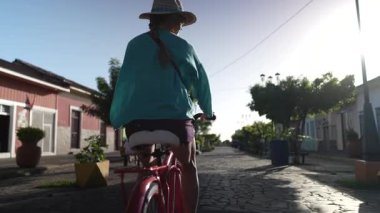 Olgun bir kadın, güneşli bir günde Orta Amerika 'nın cazibesini tecrübe ederek Granada, Nikaragua' daki Calzada sokaklarında bisiklet sürmekten hoşlanıyor..