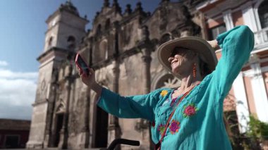 Mutlu bir turist telefonu ile Granada, Nikaragua 'daki La Merced Kilisesi' nin önünde selfie çeker. Bisiklete biniyor ve açık hava deneyiminin tadını çıkarıyor..