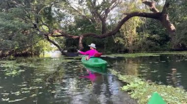 Olgun bir kadın, Nikaragua Gölü 'nün dingin sularında yemyeşil sularda kanoyla kürek çeker. O, güzel manzarayı keşfederken gülümser..