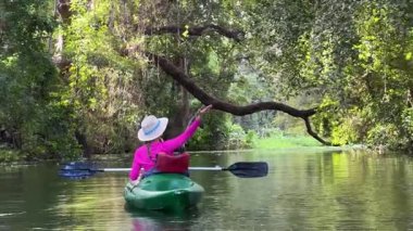 Olgun bir kadın Nikaragua, Granada 'da, Nikaragua Gölü' nün sakin sularında kano sürerken gülümsüyor. Bereketli yeşilliklerle çevrili, orman keşfi ve doğanın neşesini kucaklıyor..