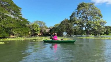 Olgun bir kadın, Granada 'daki Nikaragua Gölü' nde huzurlu bir kano gezisinin tadını çıkarıyor. Yeşilliklerle çevrili, gülümsüyor, açık hava macerasını kucaklıyor ve eğleniyor..