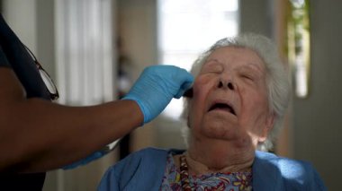 Bakıcı, sağlık merkezinde makyajlı yaşlı bir kadına özenle yardım ediyor, bağlılığı teşvik ediyor ve şefkatli bir etkileşimle rahatlığı teşvik ediyor..