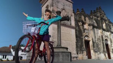Olgun bir kadın bisikletle Granada, Nikaragua 'da, La Merced Kilisesi' nin yanında, Orta Amerika 'nın canlı kültürünü ve ılık havasını tecrübe etmekten zevk alıyor..