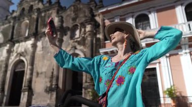 Mutlu bir turist telefonu ile Granada, Nikaragua 'daki La Merced Kilisesi' nin önünde selfie çeker. Bisiklete biniyor ve açık hava deneyiminin tadını çıkarıyor..