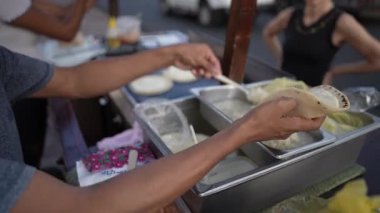 Bir sokak satıcısı Granada, Nikaragua 'da quesillo servis ediyor. Turistler hareketli pazarı keşfediyor, gün batımında otantik Orta Amerika mutfağının tadını çıkarıyorlar..