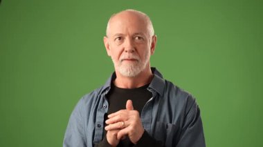 Gri saçlı olgun bir adam heyecan ve mutluluk gösterir. Kollarını yeşil bir zemine kaldırarak güçlü duygular taşır..