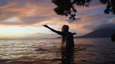 Mutlu, olgun bir kadın, Nikaragua 'daki Concepcion volkanı yakınlarında günbatımında sakin bir gölün sularının tadını çıkararak, doğanın güzelliğini kucaklıyor..