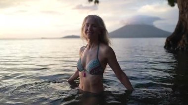 Günbatımında Concepcion Volkanı 'nın çarpıcı arka planıyla çevrili bir gölün sakin sularında mutlu ve çekici bir kadın duruyor..