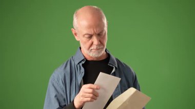 Olgun bir adam gülümsüyor ve dostça bir el sallıyor. Sıradan bir kıyafet giyiyor ve yeşil bir zemine karşı sıcak ve neşeli bir duygu taşıyor..