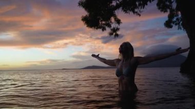 Mutlu orta yaşlı kadın, gün batımında sıcak bir gölün sularında gevşiyor. Etrafı Concepcion volkanı ve Nikaragua 'daki canlı gökyüzü manzaralarıyla çevrili..