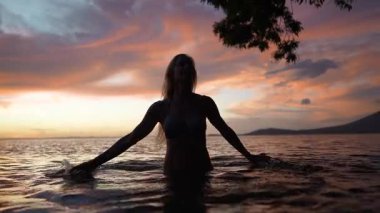 Olgun bir kadın, Concepcion Gölü 'nün ılık sularında, günbatımının nefes kesen güzelliği ve Orta Amerika' daki volkanla çevrelenmiş, neşeyle gülümsüyor..