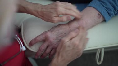 Bakıcı yaşlı kadın hastalara masaj yapıyor..