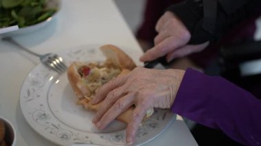 Yaşlı eklem iltihabı elleri birlikte yemek masasındaki bir tabakta sandviç keserek bir toplanma sırasında bir anlık yemek paylaşımı ve keyfini çıkarırlar..