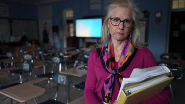 Hayal kırıklığına uğramış, mutsuz, orta yaşlı bir kadın sessiz bir sınıfta elinde dosyalar ve kağıtlarla dikiliyor. Odaklanmış ve okul yaklaşırken öğrencileriyle görüşmeye hazır görünüyor..