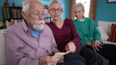 Sıcak bir oturma odasında olgun ebeveynler samimi bir mektup okurken birlikteliği kucaklarlar. Aile bağlarının sıcaklığı, ifadelerinde ve çevrelerinde açıkça görülür..