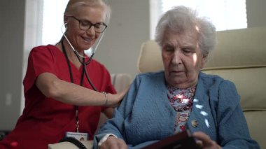 Bakıcı, sağlık merkezindeki yaşlı bir kadına özenli destek verir, ilgili bir anda etkileşimi ve bağlılığı teşvik eder..