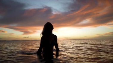 Neşeli, olgun bir kadın, Nikaragua 'daki bir gölün sakin sularında duruyor. Büyüleyici Concepcion Volkanı' nın açık kollarıyla günbatımını kutluyor..