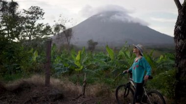 Omotepe Adası 'ndaki yemyeşil yemyeşil bisikletli güzel, son sınıf kadınına yaklaş. Concepcion volkanı arka planda görkemli bir şekilde beliriyor.